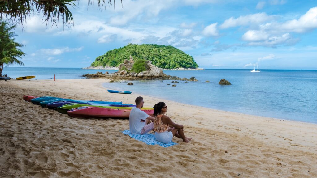 Couple at Yanui beach Phuket Thailand with kayaks on the beach, tropical beach with the blue ocean