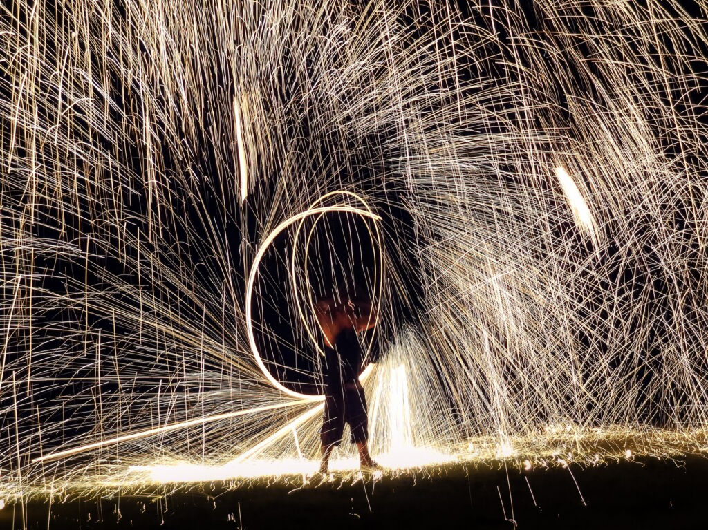 Firestarter performing amazing fire show with sparkles in the night
